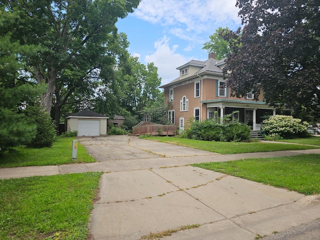 view of front of house with a porch, a garage, an outbuilding, and a front lawn