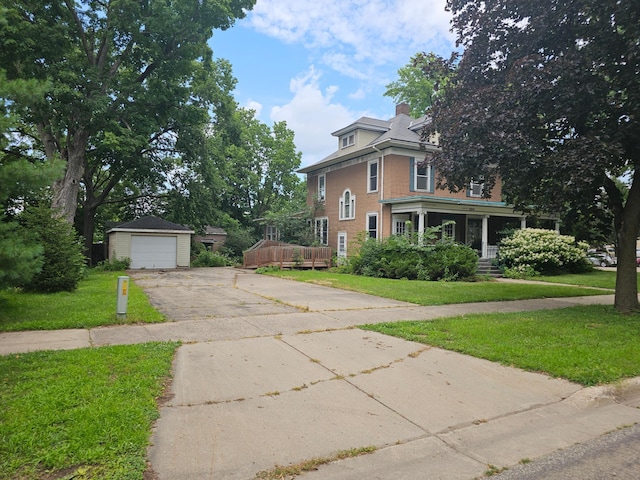 view of front facade featuring a front yard, a porch, a garage, and an outdoor structure