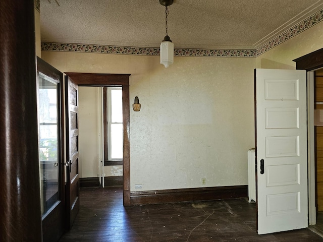 unfurnished room featuring dark hardwood / wood-style floors, radiator heating unit, and a textured ceiling