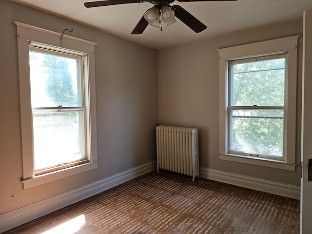 spare room with ceiling fan, radiator heating unit, and plenty of natural light