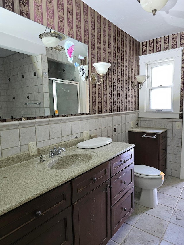 bathroom featuring vanity, tile patterned flooring, toilet, tile walls, and walk in shower