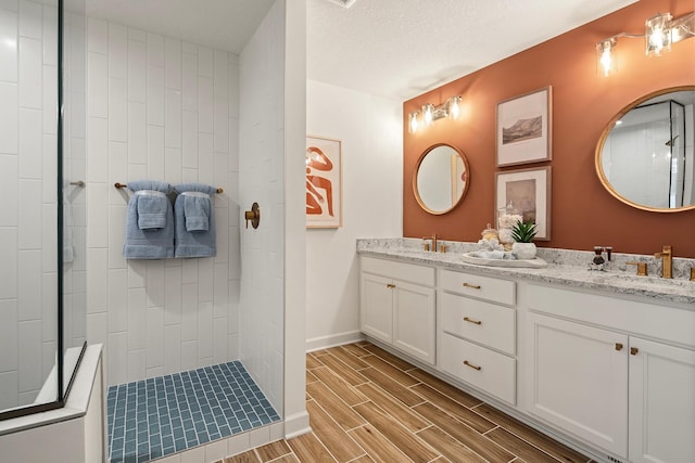 bathroom featuring vanity, a textured ceiling, and a tile shower