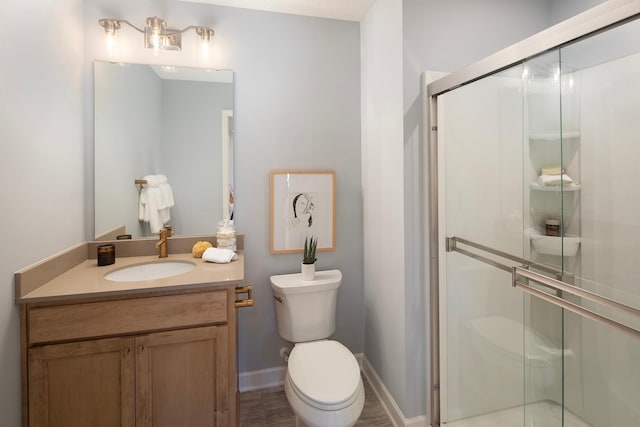 bathroom featuring toilet, an enclosed shower, and vanity