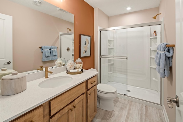 bathroom with a shower with shower door, vanity, wood-type flooring, and toilet