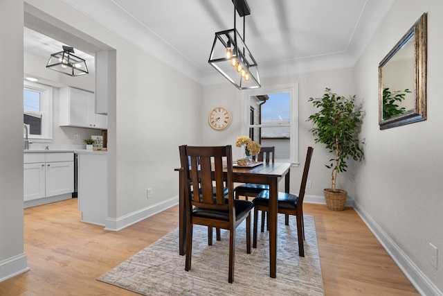 dining area featuring light wood-type flooring, crown molding, and a healthy amount of sunlight