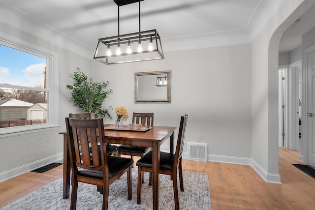 dining space with light wood-type flooring and crown molding