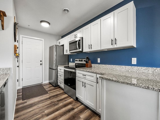 kitchen featuring white cabinetry, stainless steel appliances, light stone countertops, and dark wood-type flooring