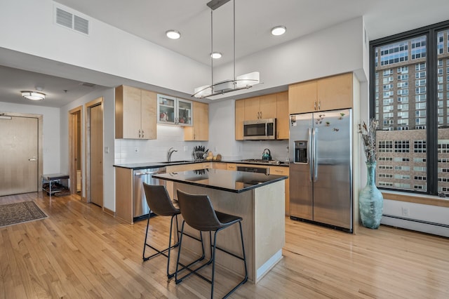 kitchen with decorative backsplash, sink, hanging light fixtures, stainless steel appliances, and light brown cabinetry