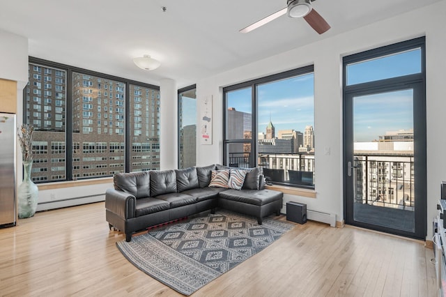 living room featuring ceiling fan, baseboard heating, and light hardwood / wood-style flooring