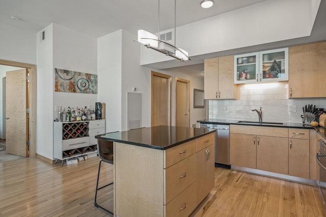 kitchen featuring stainless steel appliances, light brown cabinetry, a kitchen island, and sink