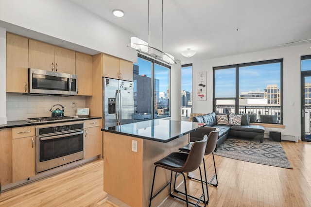 kitchen featuring backsplash, a kitchen island, light wood-type flooring, a breakfast bar area, and stainless steel appliances