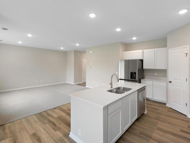 kitchen featuring hardwood / wood-style floors, sink, an island with sink, stainless steel appliances, and white cabinets