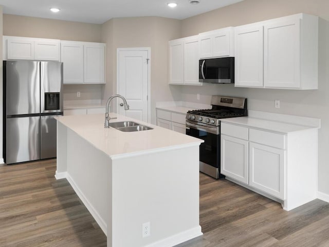 kitchen featuring sink, white cabinetry, stainless steel appliances, and an island with sink