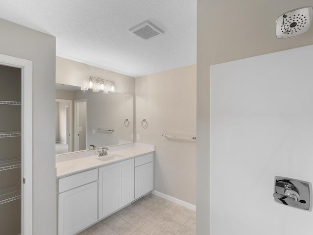 bathroom featuring a textured ceiling, tile patterned flooring, and vanity