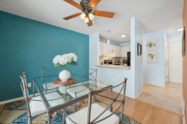 dining room with ceiling fan, sink, a textured ceiling, and light hardwood / wood-style floors