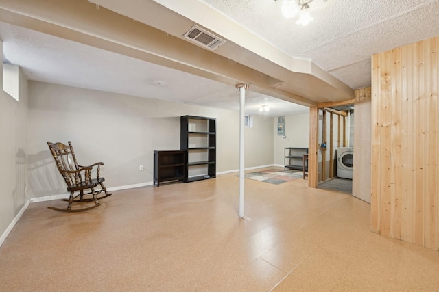 basement with washer / clothes dryer and a textured ceiling