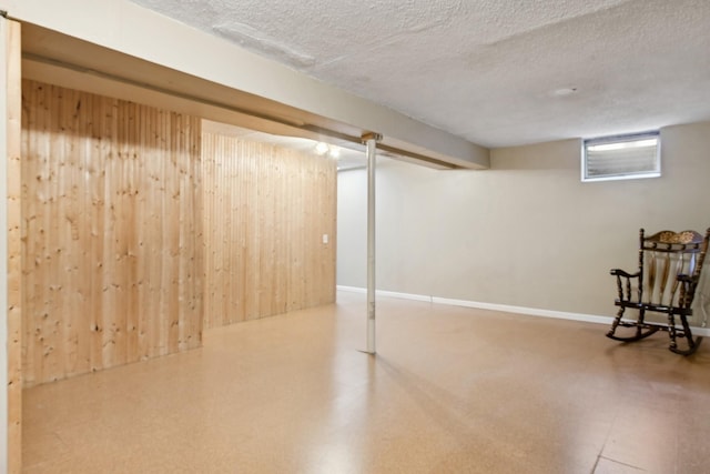 basement featuring wooden walls and a textured ceiling