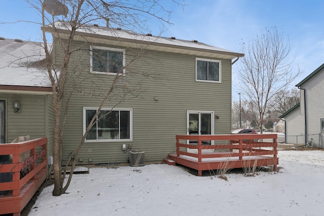 snow covered rear of property with a wooden deck and central AC