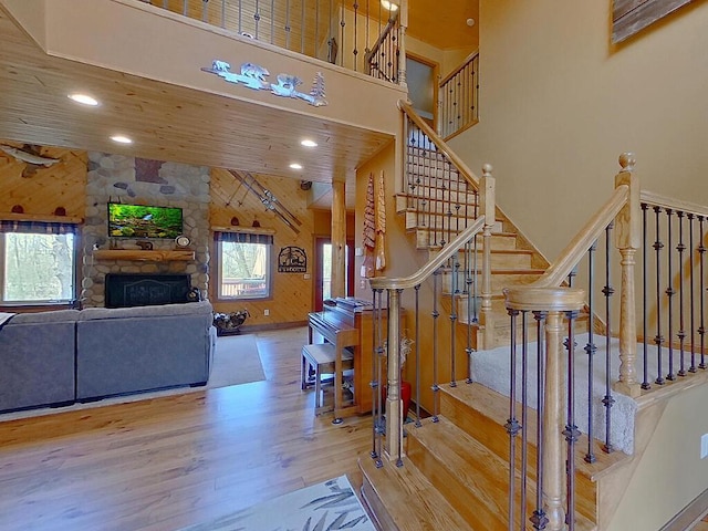 16694 206th Cir, Hutchinson, MN 55350 - staircase with wood finished floors, a high ceiling, a fireplace, recessed lighting, and wood walls