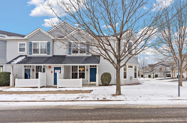 townhome / multi-family property with a porch and roof with shingles