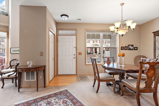 dining area with a chandelier, light carpet, visible vents, and baseboards