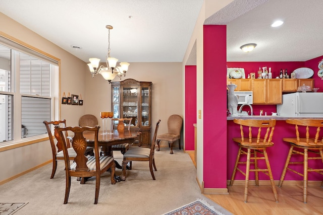 dining space with a textured ceiling, baseboards, and a notable chandelier