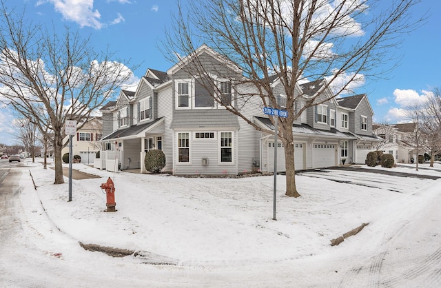 view of snowy exterior with an attached garage and a residential view