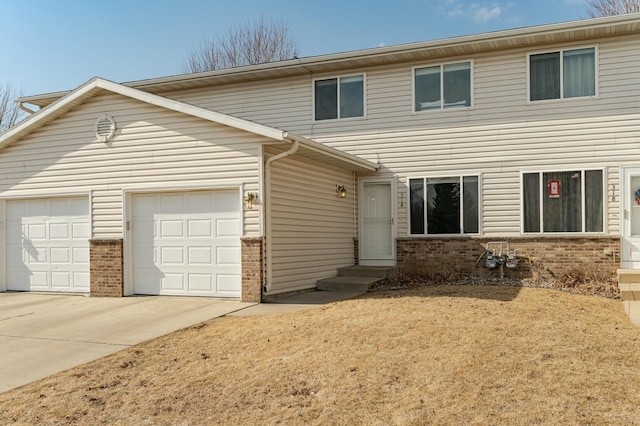 view of front of house featuring an attached garage, driveway, and brick siding