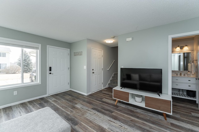 entryway featuring stairs, a textured ceiling, baseboards, and wood finished floors