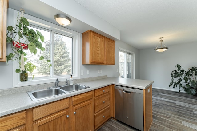 kitchen featuring a peninsula, a sink, light countertops, dishwasher, and dark wood finished floors