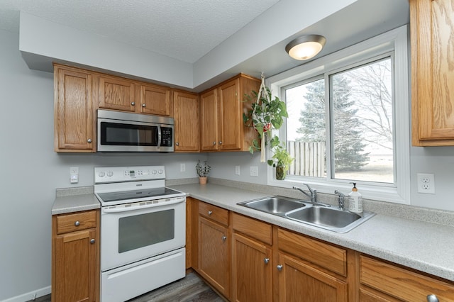 kitchen with white electric stove, light countertops, stainless steel microwave, a sink, and a textured ceiling