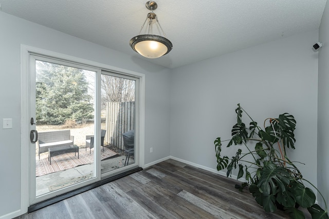 empty room with a textured ceiling, dark wood-style flooring, and baseboards