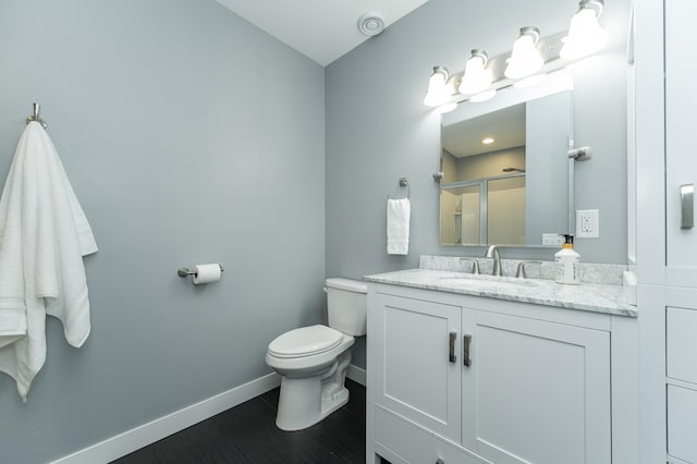 full bathroom featuring toilet, a stall shower, vanity, wood finished floors, and baseboards