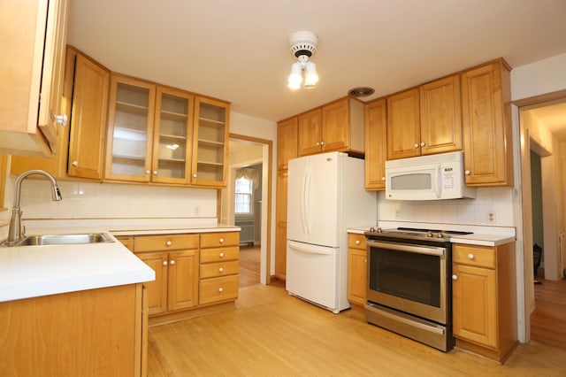 kitchen with tasteful backsplash, white appliances, sink, and light wood-type flooring