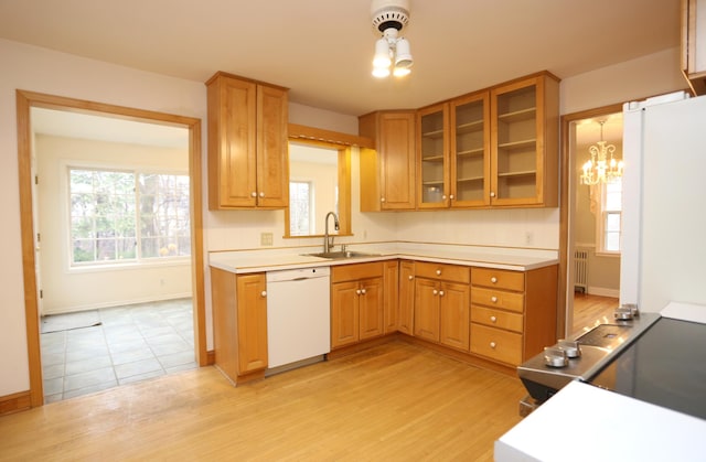 kitchen featuring white dishwasher, sink, decorative light fixtures, and light hardwood / wood-style flooring