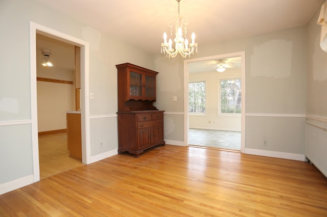 unfurnished dining area with radiator, ceiling fan with notable chandelier, and light hardwood / wood-style floors