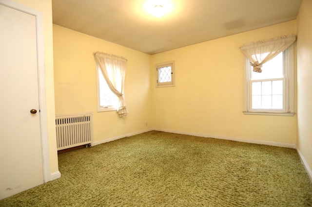 carpeted empty room with radiator and plenty of natural light