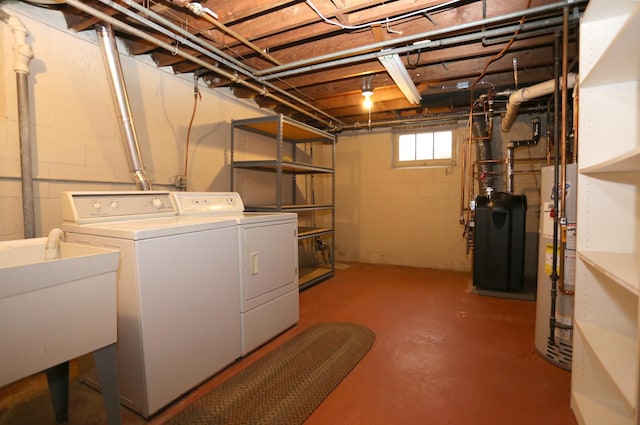 clothes washing area featuring sink, water heater, and washing machine and clothes dryer