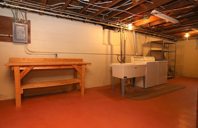 basement with sink, washing machine and clothes dryer, and electric panel