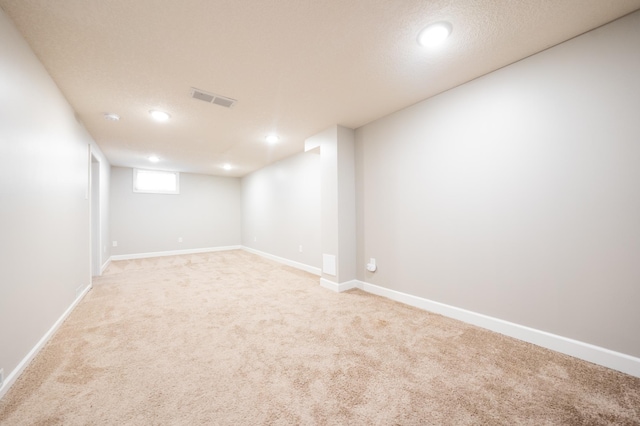 basement with light colored carpet and a textured ceiling