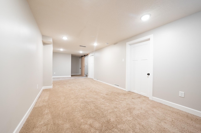 basement with light colored carpet and a barn door