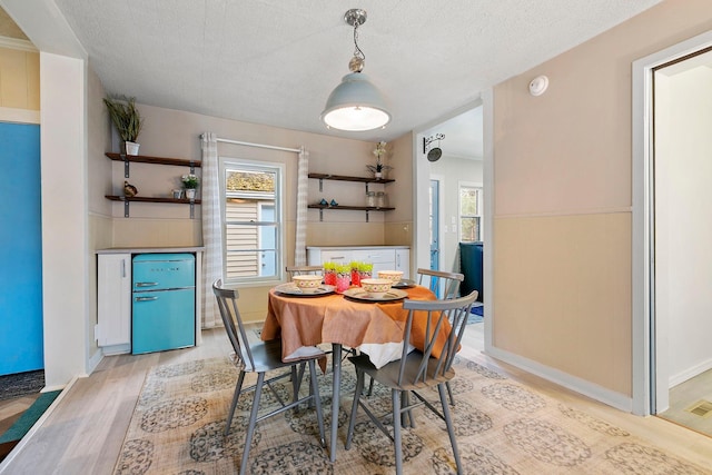 dining area featuring a textured ceiling and light hardwood / wood-style flooring