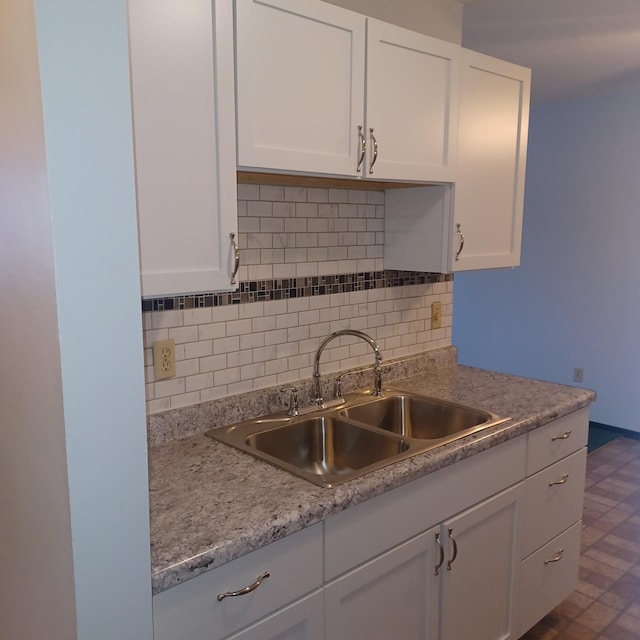 kitchen with tasteful backsplash, white cabinetry, and sink