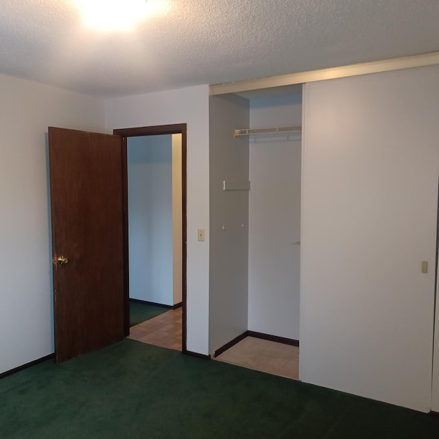 unfurnished bedroom with a closet, a textured ceiling, and dark colored carpet