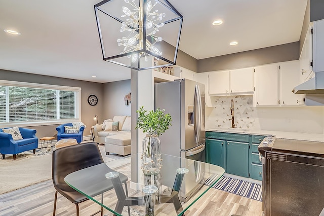 kitchen featuring sink, white cabinets, an inviting chandelier, tasteful backsplash, and stainless steel refrigerator with ice dispenser