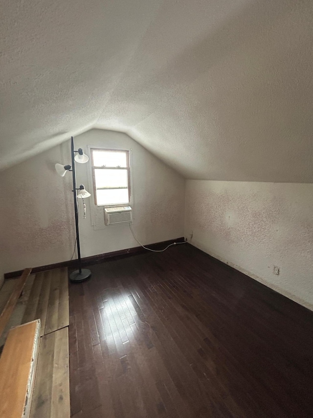 additional living space featuring dark hardwood / wood-style floors, lofted ceiling, and a textured ceiling