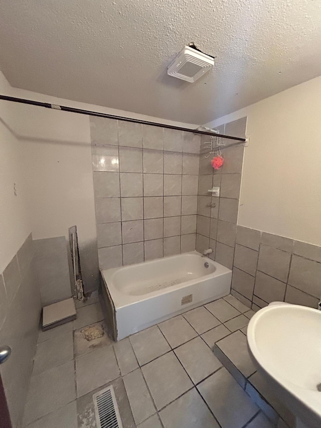 bathroom with tile patterned floors, tile walls, a textured ceiling, and tiled shower / bath