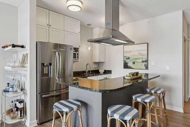 kitchen with white cabinetry, island range hood, stainless steel fridge, and a breakfast bar