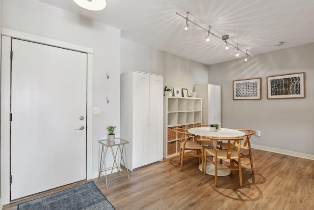 dining room with rail lighting and light hardwood / wood-style flooring