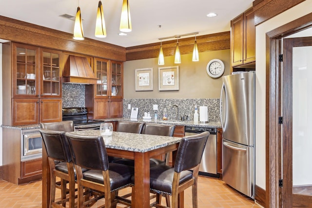 kitchen with pendant lighting, tasteful backsplash, stainless steel appliances, and premium range hood